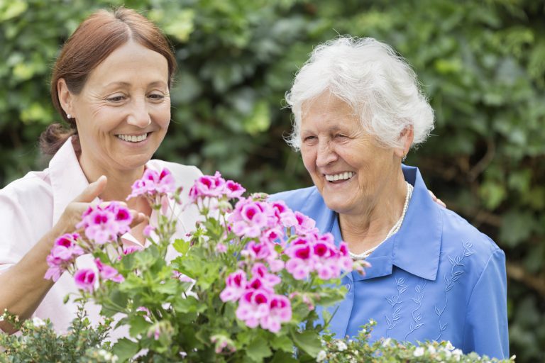 Caregiver with Senior Tending Flowers