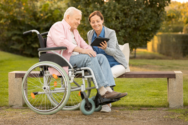Caregiver with man in wheelchair on a bench