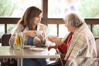 Care worker having tea with senior lady