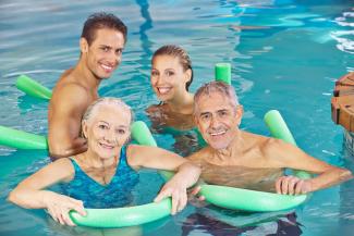 Elderly couple in pool with son and daughter in law