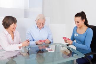 Senior couple playing cards with home caregiver