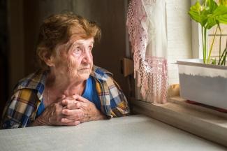 Lonely senior lady looking out window
