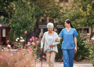 Senior walking outside with caregiver on a nice day