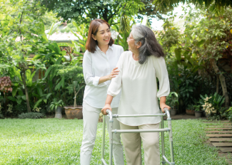 Senior and adult child out for a walk in the spring, using walker for mobility assistance