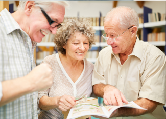 Seniors socializing and looking at a book together in the library