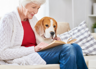 Senior woman reading a book with her dog