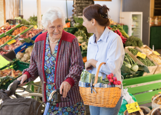 Caregiver grocery shopping with senior, ensuring they get healthy and nutritious ingredients for meals