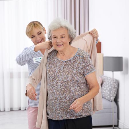 Caregiver putting sweater on senior