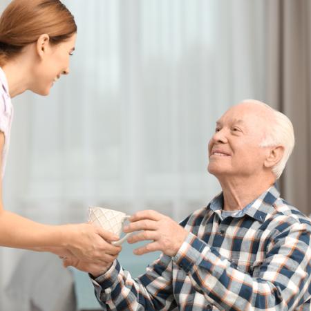 Senior receiving cup of tea from caregiver