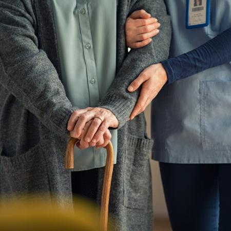 Caregiver helping senior with cane and mobility issues