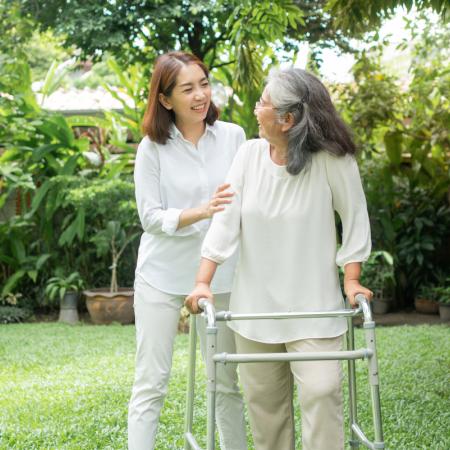 Senior and adult child out for a walk in the spring, using walker for mobility assistance
