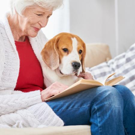 Senior woman reading a book with her dog