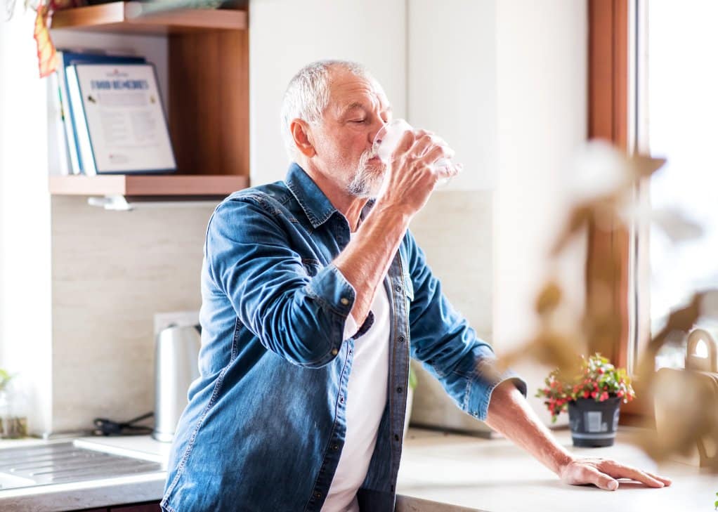 Senior hydrating with a glass of water